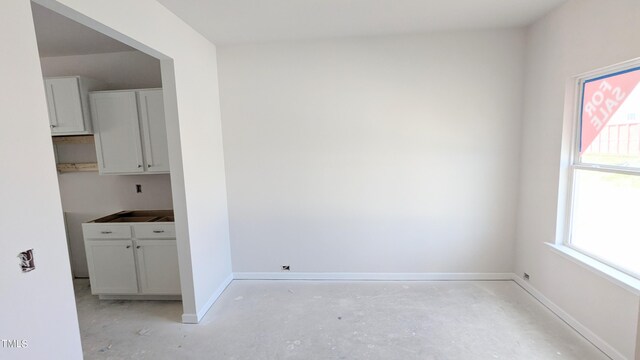 unfurnished dining area featuring plenty of natural light, baseboards, and concrete floors