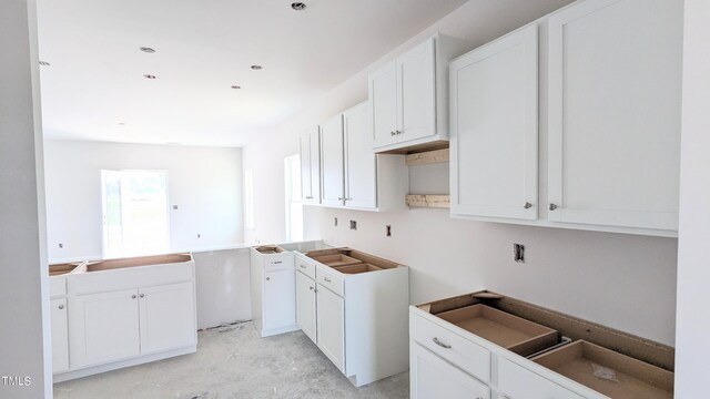 kitchen with concrete flooring and white cabinets
