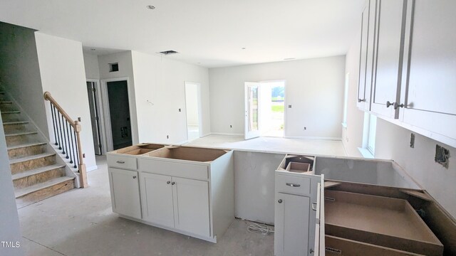 kitchen featuring unfinished concrete flooring, white cabinets, and open floor plan