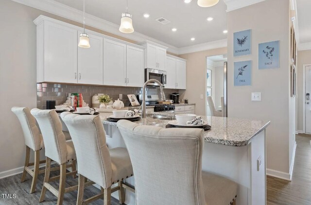 kitchen with stainless steel appliances, ornamental molding, backsplash, white cabinetry, and baseboards