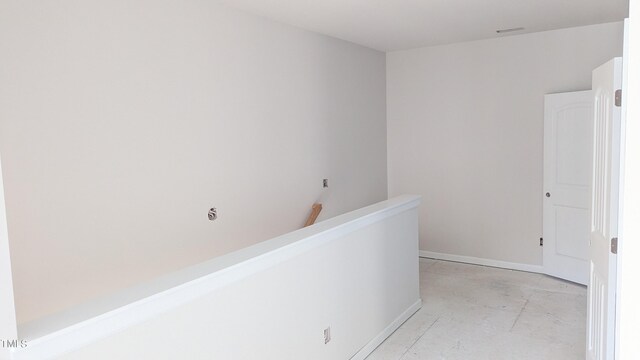 hall featuring baseboards and concrete floors