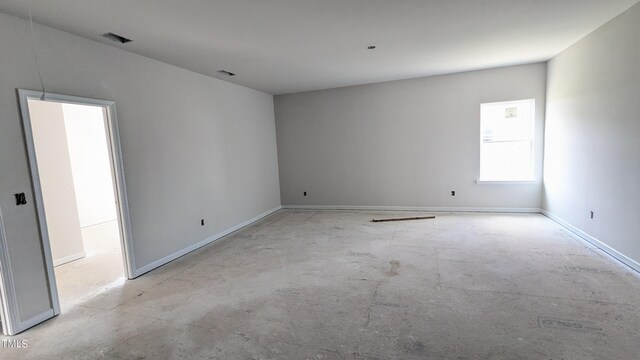 empty room with concrete flooring and baseboards