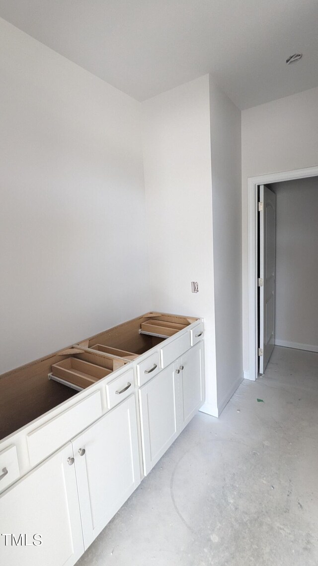 kitchen featuring unfinished concrete flooring and white cabinetry