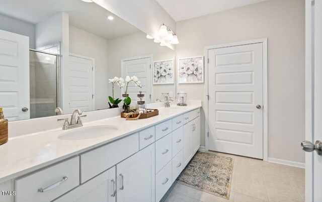 bathroom with a stall shower, double vanity, tile patterned floors, and baseboards