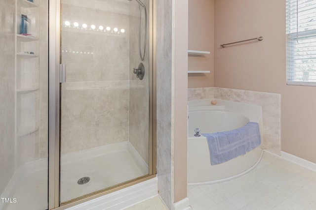 bathroom featuring a stall shower, a bath, and baseboards