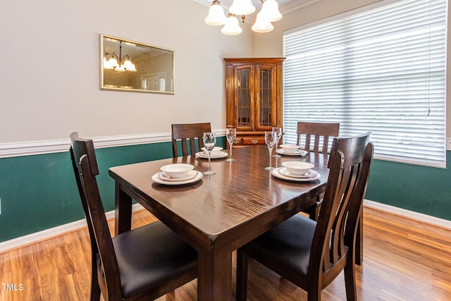 dining room with a chandelier, wood finished floors, baseboards, and ornamental molding