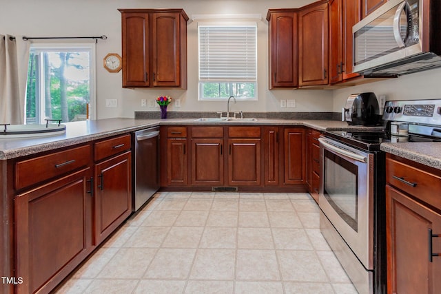 kitchen featuring appliances with stainless steel finishes, healthy amount of natural light, a sink, and dark countertops