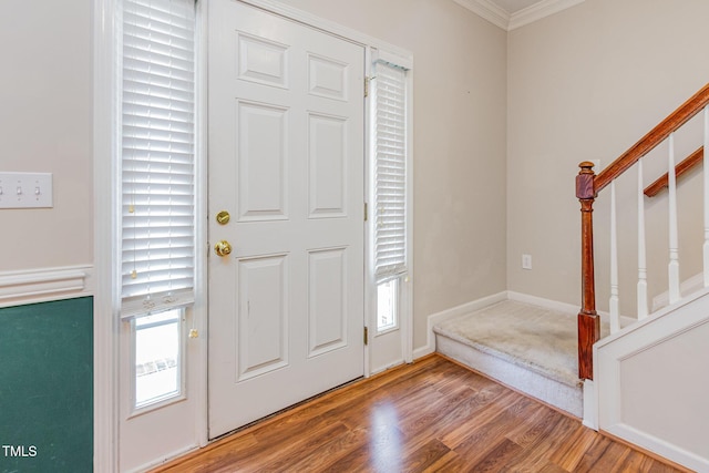 foyer entrance featuring stairs, ornamental molding, wood finished floors, and baseboards