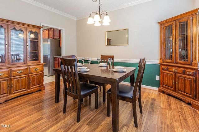 dining room with light wood-type flooring, a chandelier, and crown molding
