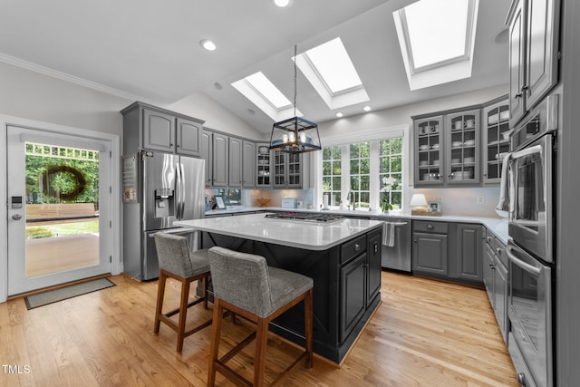 120 Harmony Hill Ln, Cary, NC 27513 - kitchen with appliances with stainless steel finishes, a skylight, gray cabinets, a center island, and glass insert cabinets