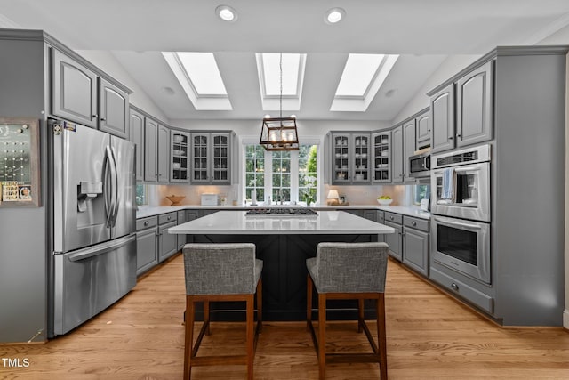 120 Harmony Hill Ln, Cary, NC 27513 - kitchen with gray cabinetry, stainless steel appliances, a skylight, vaulted ceiling, and glass insert cabinets