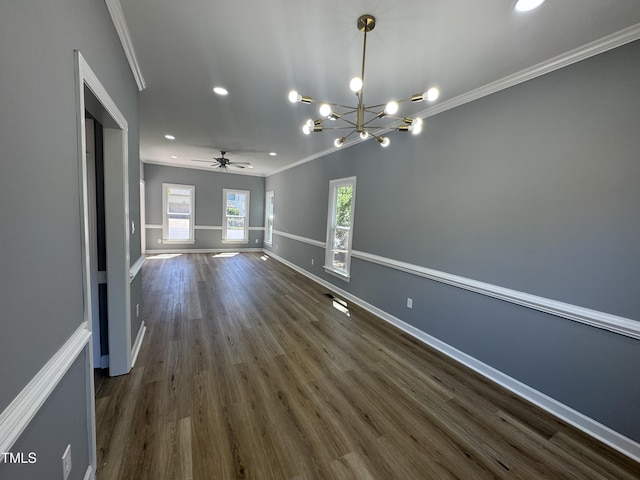 unfurnished dining area featuring ornamental molding, dark wood-style floors, ceiling fan, a chandelier, and baseboards