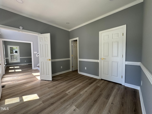 unfurnished bedroom with wood finished floors, ornamental molding, and baseboards