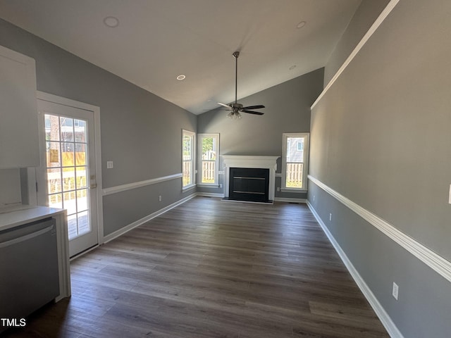 unfurnished living room with healthy amount of natural light, a glass covered fireplace, ceiling fan, dark wood-style flooring, and high vaulted ceiling