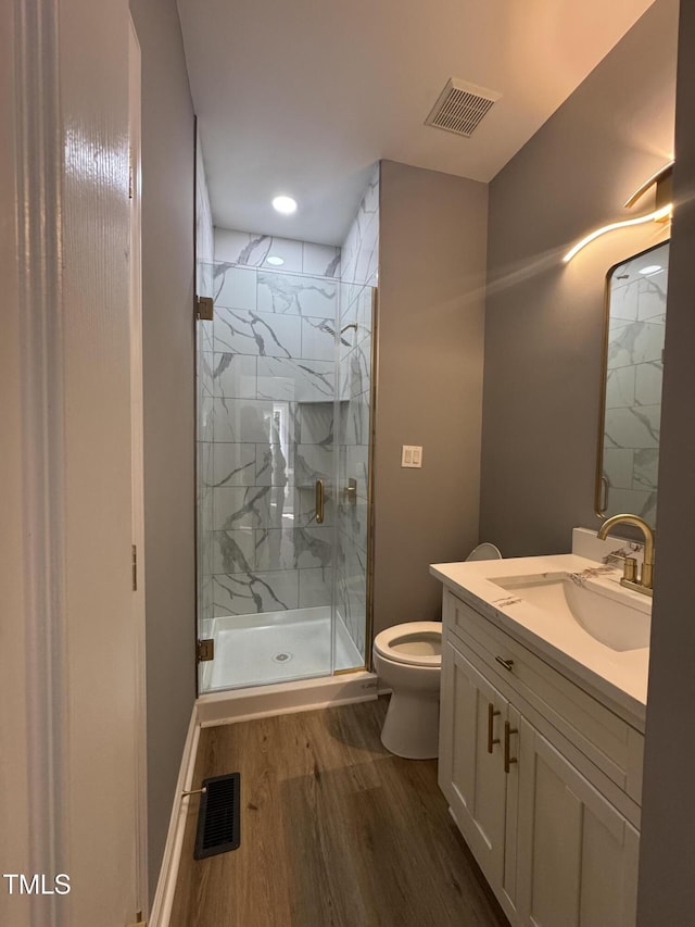 full bath featuring wood finished floors, vanity, a marble finish shower, and toilet
