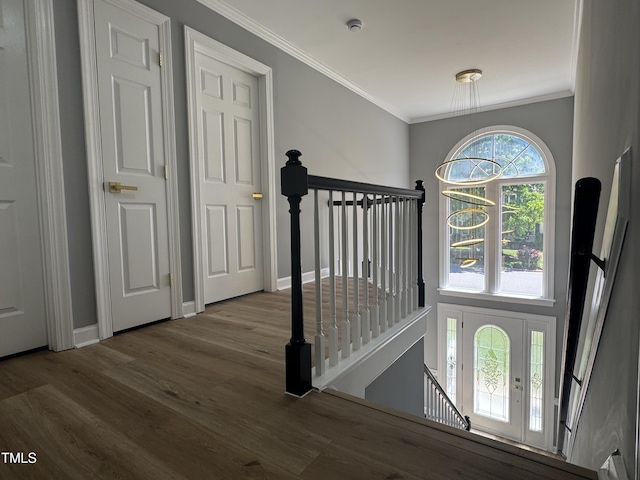 entryway with wood finished floors, ornamental molding, and baseboards
