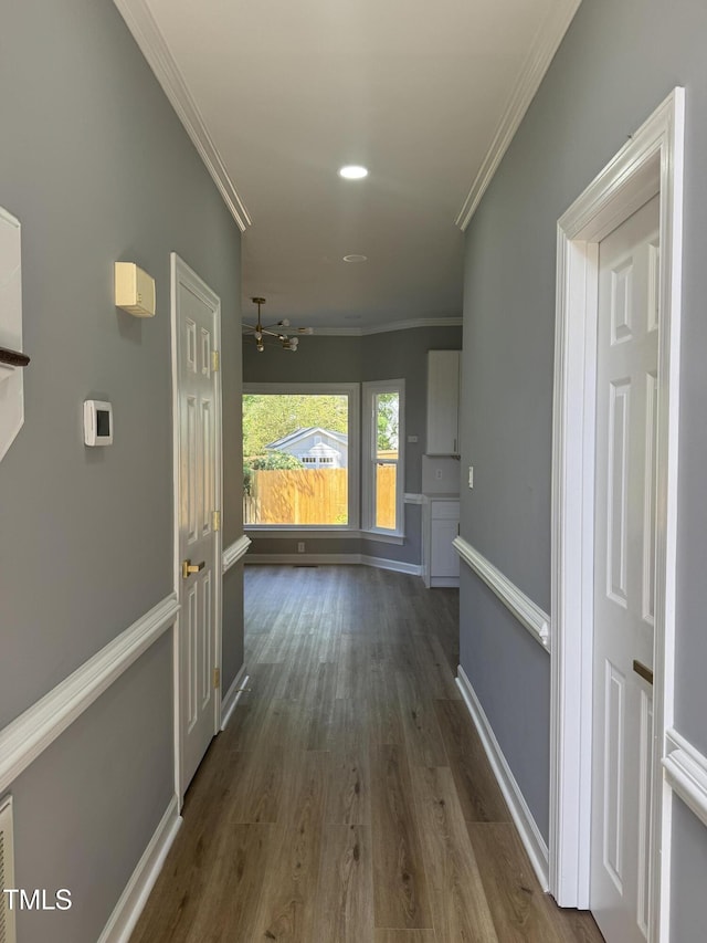 hallway with ornamental molding, dark wood-type flooring, a chandelier, baseboards, and recessed lighting