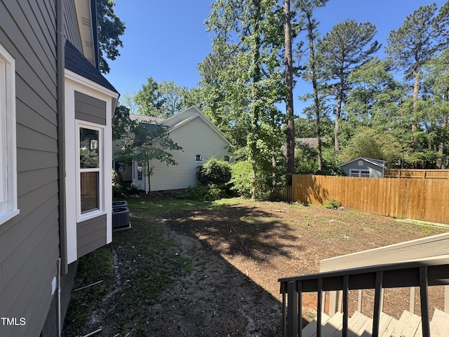 view of yard featuring fence and central AC