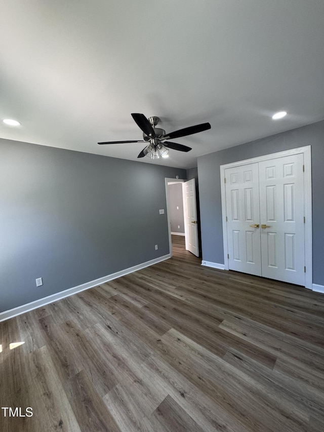 unfurnished bedroom featuring baseboards, wood finished floors, a closet, and ceiling fan