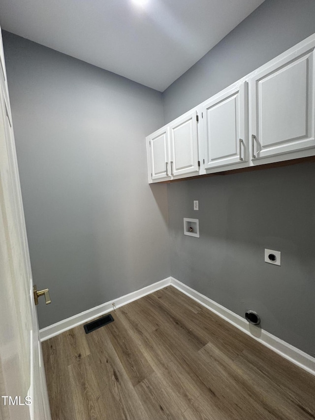 washroom with cabinet space, hookup for an electric dryer, dark wood-type flooring, hookup for a washing machine, and baseboards