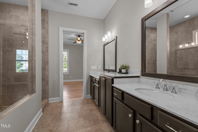 full bathroom with a ceiling fan, baseboards, two vanities, and a tile shower