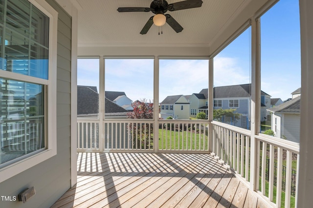 sunroom with a residential view and a ceiling fan