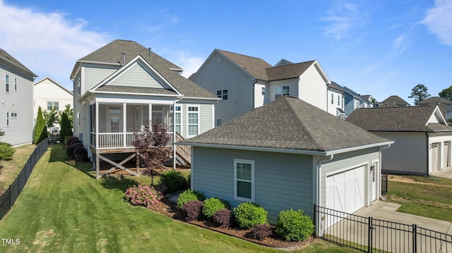back of property with roof with shingles, a sunroom, a garage, driveway, and a residential view