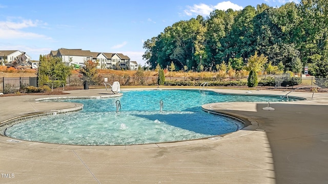 community pool featuring fence, a patio, and a residential view