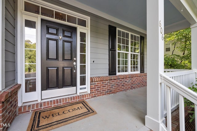property entrance featuring covered porch and brick siding
