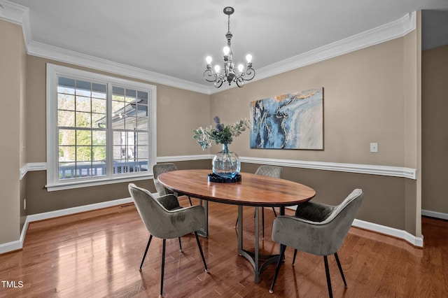 dining room with a chandelier, crown molding, baseboards, and wood finished floors