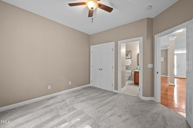 unfurnished bedroom featuring light colored carpet, baseboards, connected bathroom, and a closet