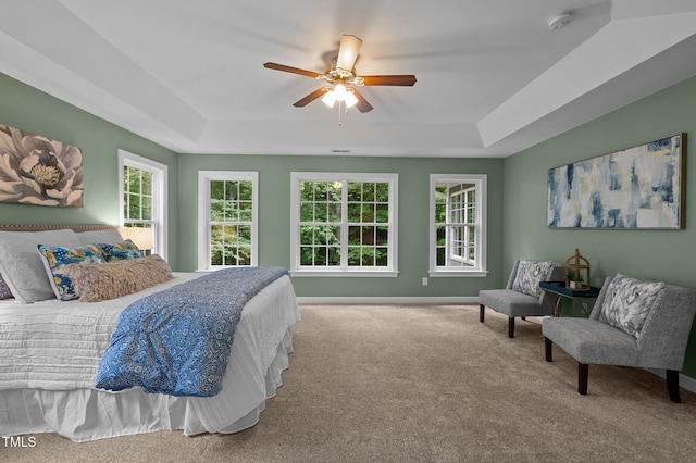 carpeted bedroom with a tray ceiling, baseboards, and ceiling fan