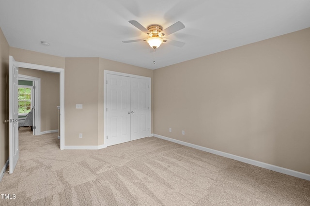 unfurnished bedroom featuring light carpet, baseboards, a closet, and a ceiling fan