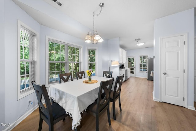 dining area with a chandelier, baseboards, light wood finished floors, and plenty of natural light