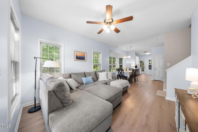 living room with light wood finished floors, a ceiling fan, and baseboards