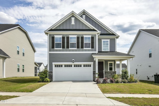 craftsman-style home featuring board and batten siding, an attached garage, a front lawn, concrete driveway, and stone siding