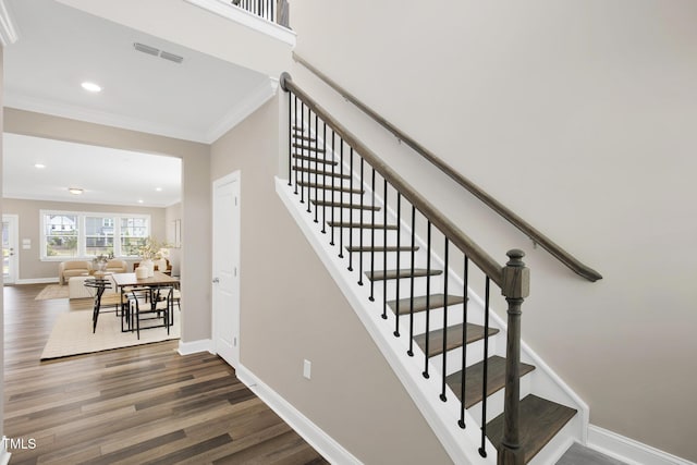 staircase with ornamental molding, wood finished floors, baseboards, and recessed lighting
