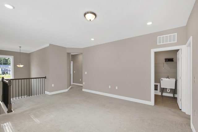 empty room featuring light carpet, baseboards, recessed lighting, and a sink