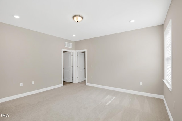 spare room with light colored carpet, baseboards, and recessed lighting