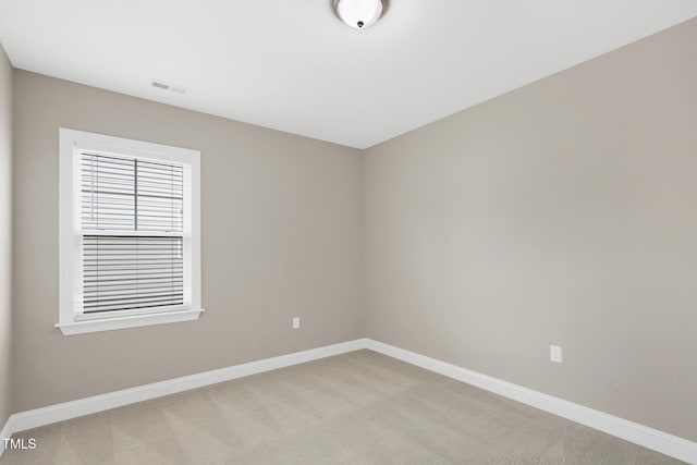 spare room featuring baseboards and light carpet