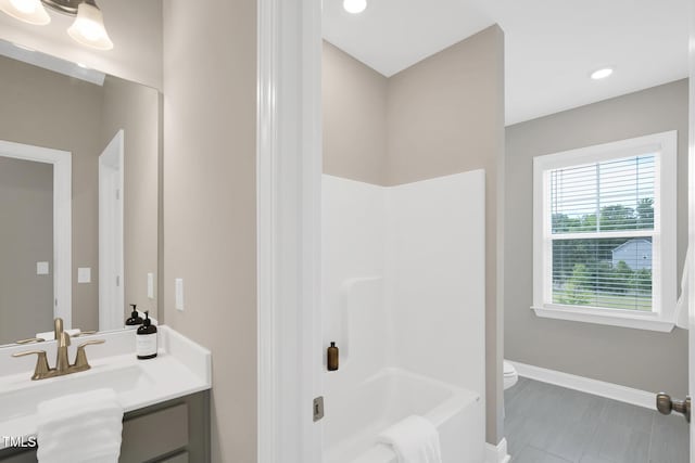 full bathroom with baseboards, vanity, toilet, and washtub / shower combination