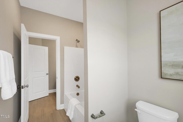 bathroom featuring toilet, bathing tub / shower combination, and baseboards
