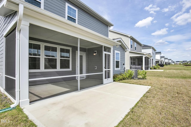 back of property with a sunroom, a lawn, a patio area, cooling unit, and a residential view