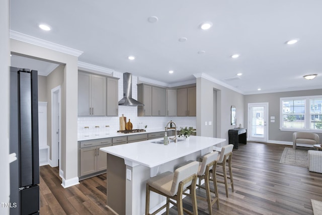 kitchen featuring gray cabinetry, wall chimney exhaust hood, a sink, dark wood-type flooring, and ornamental molding