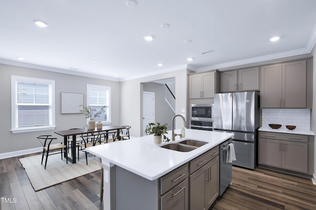 kitchen featuring gray cabinets, appliances with stainless steel finishes, a sink, crown molding, and dark wood finished floors
