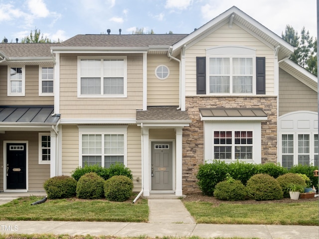townhome / multi-family property featuring stone siding, a shingled roof, and a standing seam roof