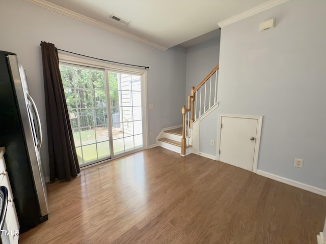 spare room with wood finished floors, crown molding, stairs, and baseboards