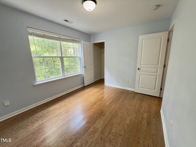 unfurnished bedroom with wood finished floors, baseboards, and a closet