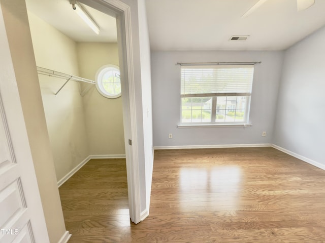unfurnished bedroom featuring multiple windows, wood finished floors, and baseboards