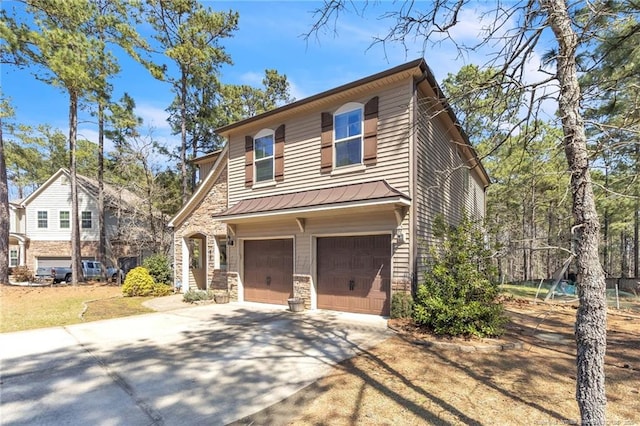 view of front of property featuring driveway, stone siding, an attached garage, and a standing seam roof